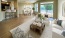 a living room with a large rug, chairs, couches and a large window