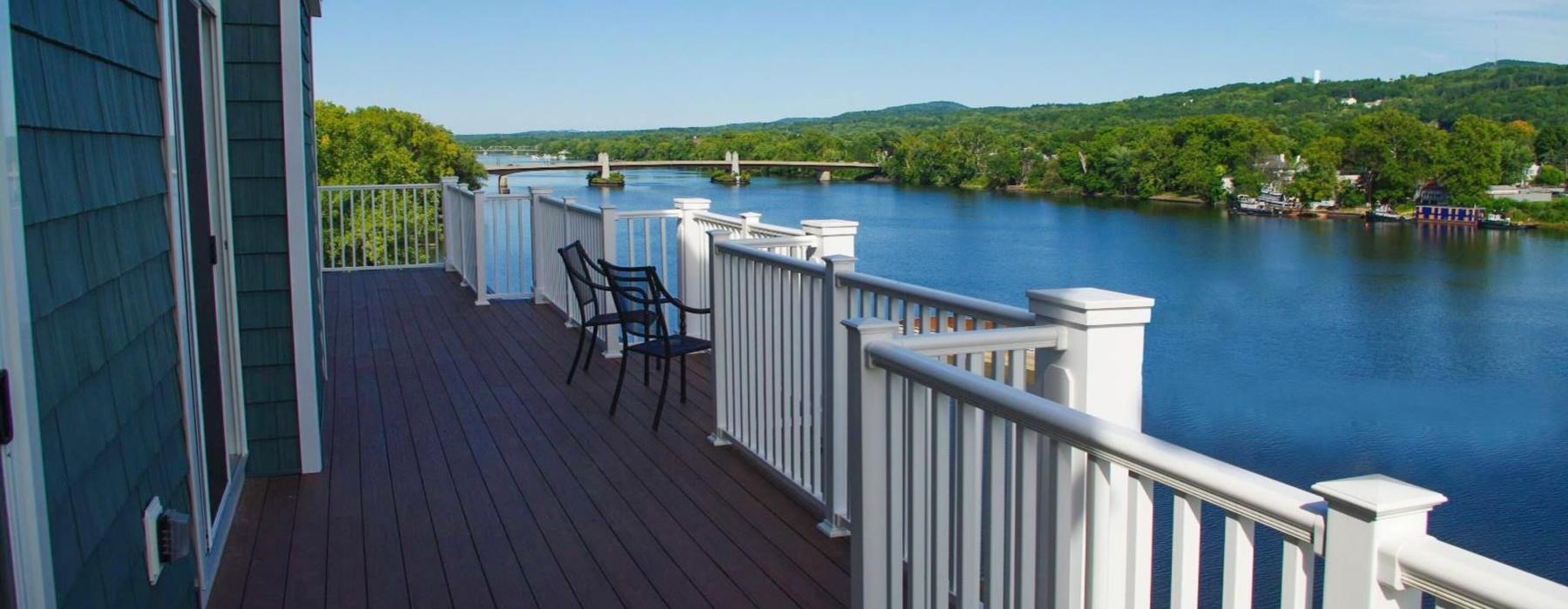 a deck with chairs and a body of water in the background