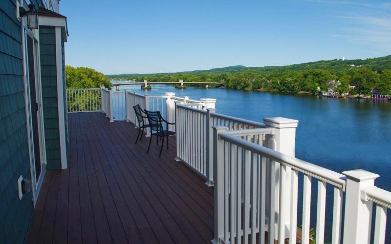 a deck with chairs and a body of water in the background