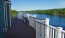 a deck with chairs and a body of water in the background